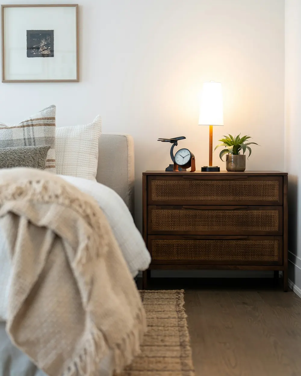 Camera da letto accogliente con biancheria chiara e comodino in legno
