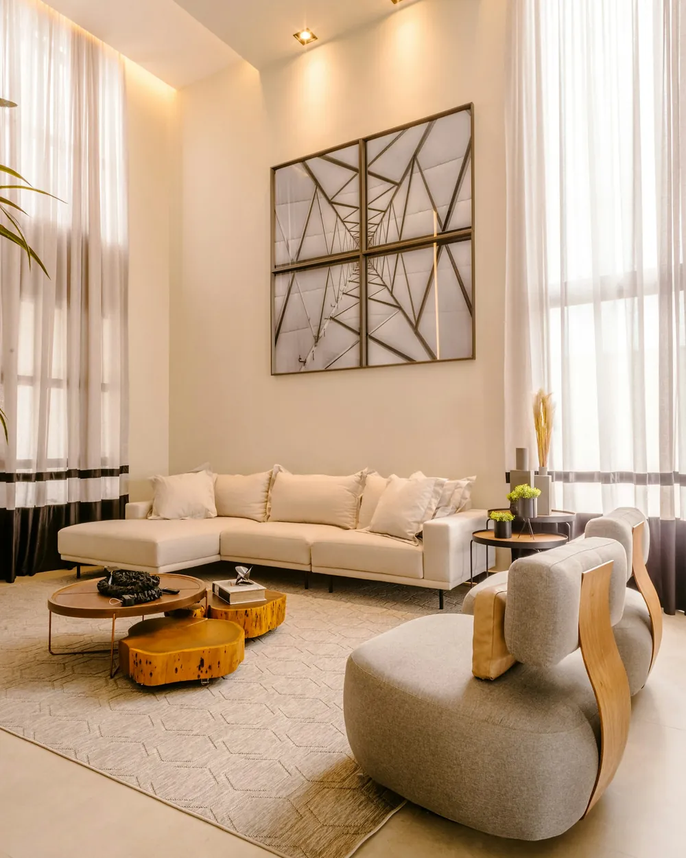 Salone di design a doppia altezza, con divani chiari e grandi tende